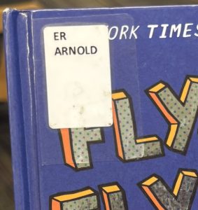 A closeup of the book "Fly Guy and Fly Girl" focused on the spine label in the upper left corner of the cover. The spine label reads "ER ARNOLD."