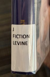 A close up of the spine on the book "The Wish," focused on the spine label. The spine label reads "J FICTION LEVINE."