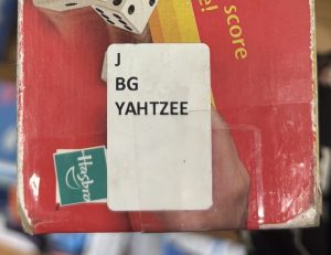 A closeup of the side of the box of the game "Yahtzee," focusing on the spine label. The spine label reads "J BG YAHTZEE."