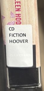 A closeup of the spine on the audiobook "It Ends With Us," focusing on the spine label. The spine label reads "CD FICTION HOOVER."