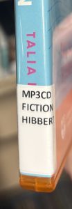 A closeup of the spine on the audiobook "Act Your Age Eve Brown," focusing on the spine label. The spine label reads "MP3CD FICTION HIBBERT."