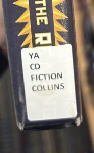 A closeup of the spine on the audiobook "Sunrise on the Reaping," focusing on the spine label. The spine label reads "YA CD FICTION COLLINS."