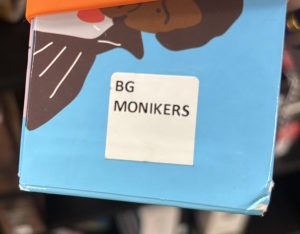 A closeup of the side of the box for the board game "Monikers," focusing on the spine label. The spine label reads "BG MONIKERS."