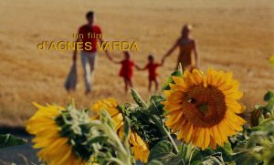 A still from Le Bonheur. It shows sunflowers in the foreground and a family in the background